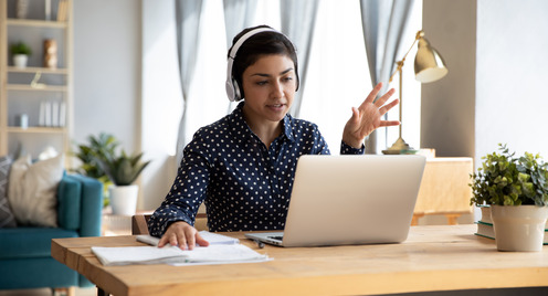 Frau mit Kopfhörern arbeitet im Homeoffice am Laptop