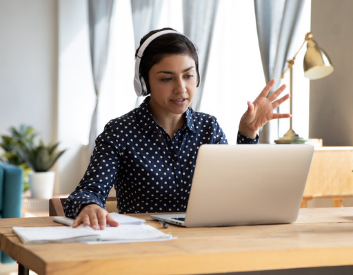 Junge Frau sitzt am Schreibtisch und arbeitet an einem Notebook