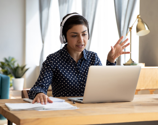 Junge Frau sitzt am Schreibtisch und arbeitet an einem Notebook
