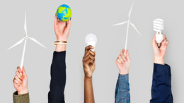 [Translate to English:] Verschiedene Personen stecken ihre Hände in die Höhe und halten jeweils einen Gegenstand in der Hand, der für Klimaschutz beziehungsweise die Energiewende steht: Windräder, eine Miniatur-Erdkugel, eine LED-Leuchte sowie eine Energiesparlampe.
