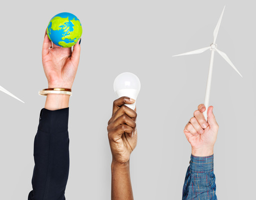 Verschiedene Personen strecken ihre Hände in die Höhe und halten jeweils einen Gegenstand in der Hand, der für Klimaschutz beziehungsweise die Energiewende steht: Windräder, eine Miniatur-Erdkugel, eine LED-Leuchte sowie eine Energiesparlampe.