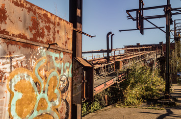 Vor einer stillgelegten Industrieanlage im Landschaftspark Duisburg-Nord ist eine mit Graffiti bespr&uuml;hte Wand zu sehen.