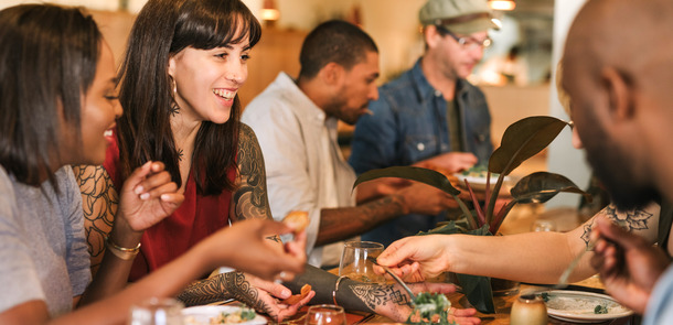 Smiling young friends enjoying dinner together in a trendy bistro(© © mavoimages - stock.adobe.com)