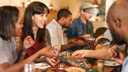 verschiedene Menschen sitzen zusammen am tisch und essen