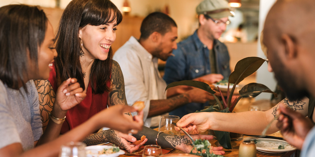 verschiedene Menschen sitzen zusammen am tisch und essen