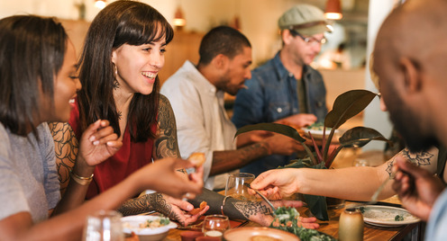 verschiedene Menschen sitzen zusammen am tisch und essen