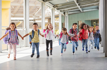 Grundschulkinder rennen händchenhaltend durch den Korridor