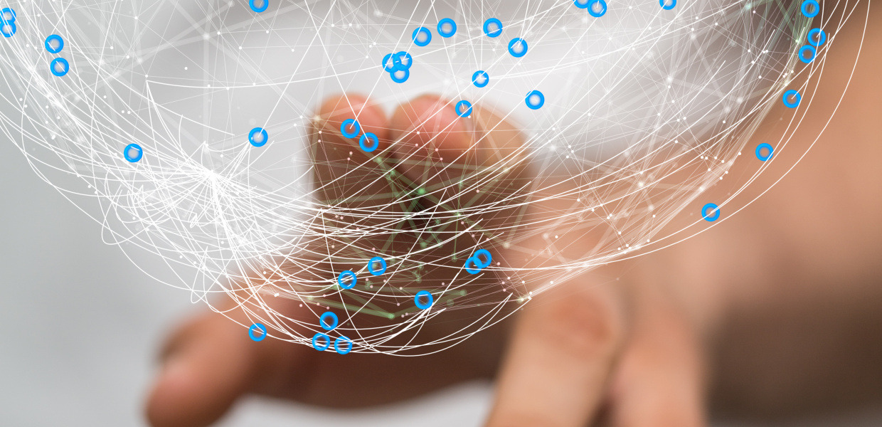 Une personne touche un graphique informatique avec deux doigts qui représente une balle ou un globe composé de lignes et de points connectés. Le graphique est représentatif d'un réseau.