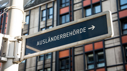 man sieht ein Straßenschild mit der Aufschrift "Ausländerbehörde"
