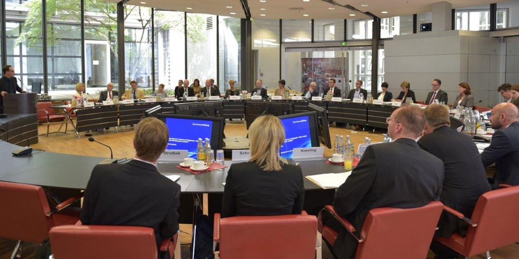 Viele Personen sitzen an einem runden Konferenztisch in Berlin und beraten sich