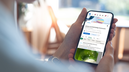 Eine Person hält ein Handy, auf dem Handydisplay ist die Startseite des LinkedIn Kanal zu sehen.