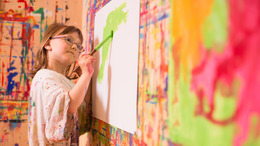 Fotoaufnahmen am 11.5.2016 im Kinderhaus Melle-Buer, ein Kind mit Malerkittel, malt ein Bild an einer Wand.
