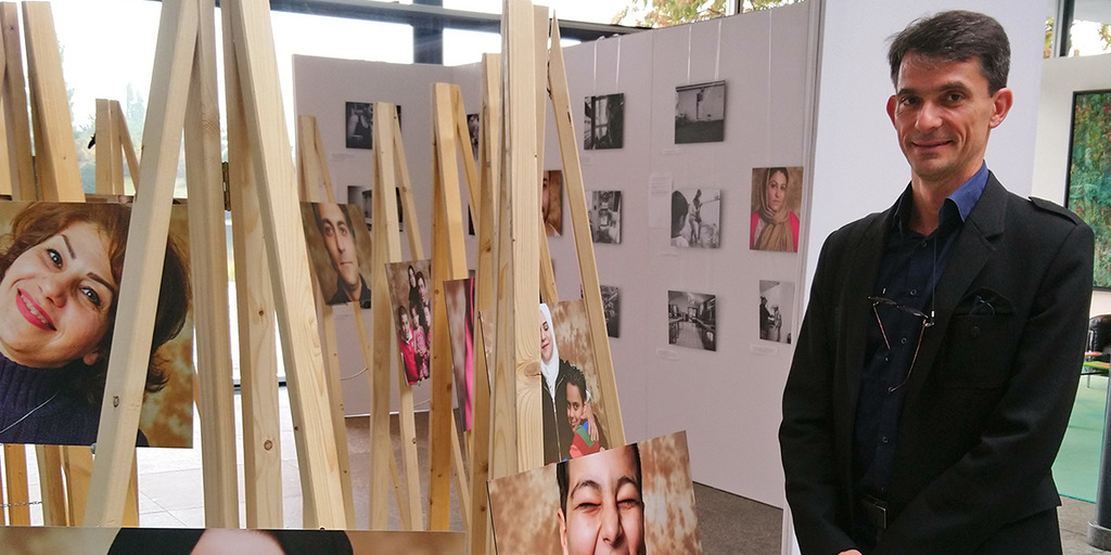 Der Fotograf Thomas Byczkowski steht vor der Fotoausstellung Menschen keine Zahlen im Foyer der Bertelsmann Stiftung