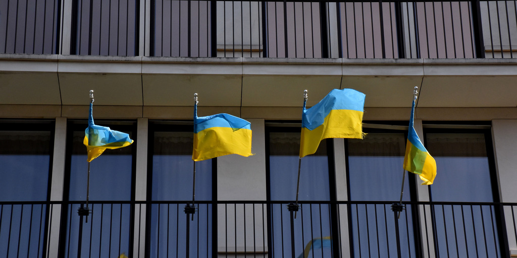 mehrere Ukraineflaggen hängen am Balkongerüst eines Gebäudes