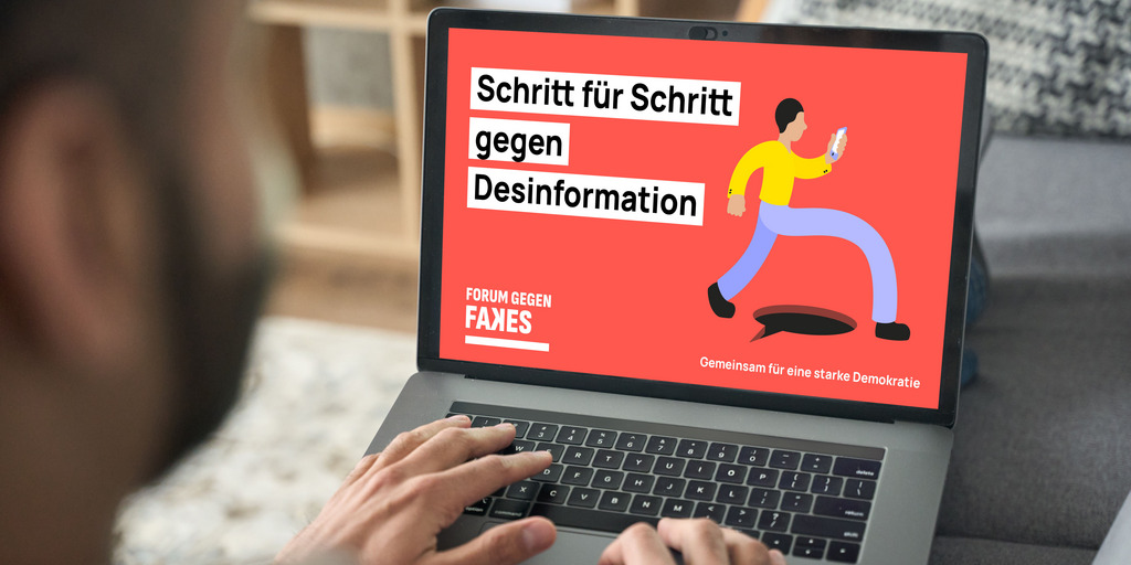 A man is typing on the keyboard of his laptop on which an image with the "Forum against Fakes" logo and the text "Step for step against disinformation" can be seen.