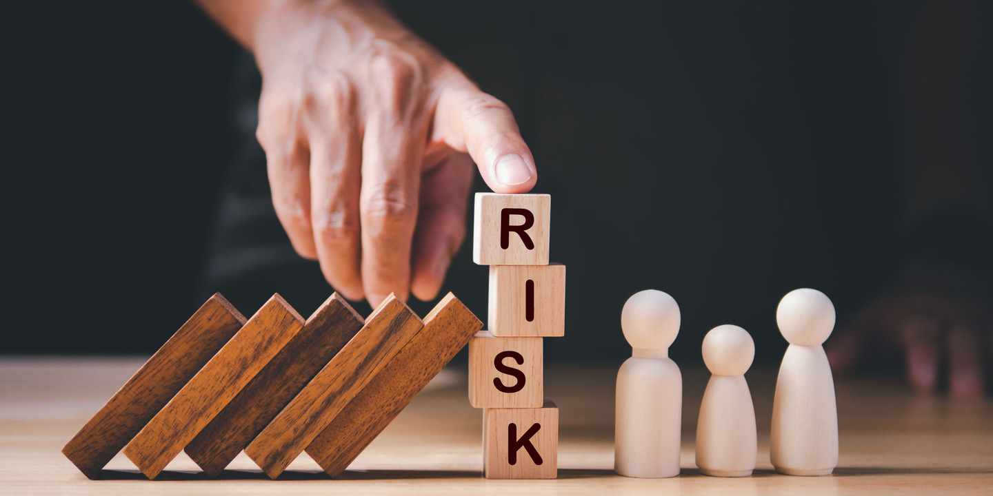 Hand hält Würfel mit der Aufschrift Risk