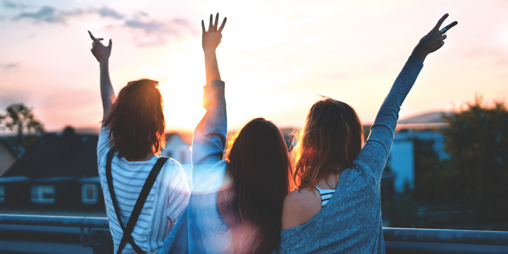 Three women raise their hands in joy