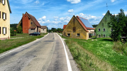 Eine verlassene Straße im ländlichen Bayern mit heruntergekommenen Häusern.
