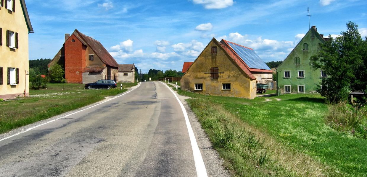 (© tpsdave/pixabay.com - Public Domain) Eine verlassene Straße im ländlichen Bayern mit heruntergekommenen Häusern.