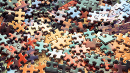 Many colorful puzzle pieces lie jumbled up on a surface