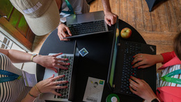 Personen am Tisch die am Laptop arbeiten