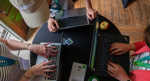 Personen am Tisch die am Laptop arbeiten