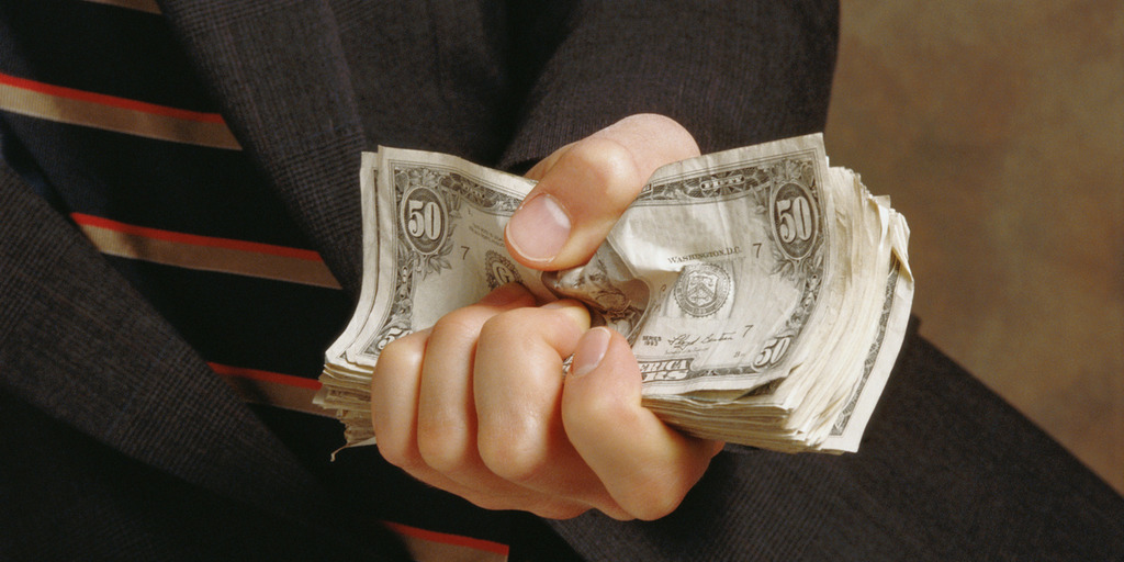 Ein Mann hält Dollar-Scheine in der Hand.