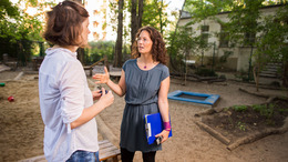 Zwei Personen, die sich auf dem Außengelände einer Kita unterhalten