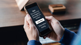 Twi white hands holding a smart phone. On the Screen it says "Alert. This content has been flagged by independent fact-checkres. Proceed with caution before sharing."