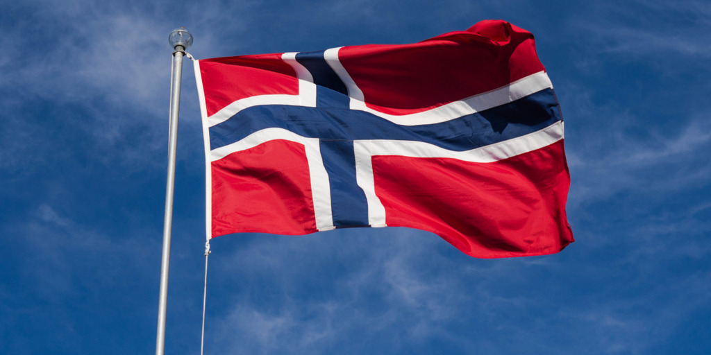 Die Flagge Norwegens weht an einem Fahnenmast vor blauem Himmel