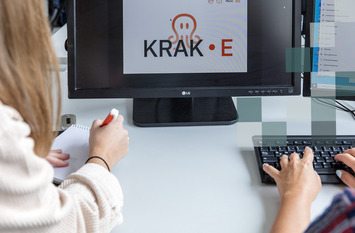 Zwei Personen sitzen am Schreibtisch vor einem Bildschirm. Auf dem Bildschirm ist das Programm "Krake" zu sehen