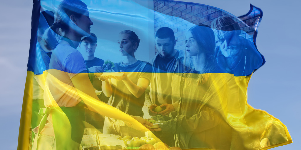 Ukrainische Flagge in der schemenhaft Menschen bei der Essensausgabe zu sehen sind
