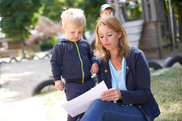 Eine Pädagogin liest einem kleinen Jungen etwas von einem Dokument vor.