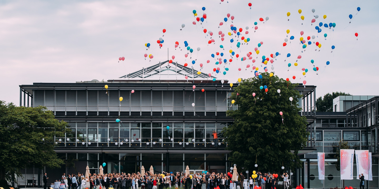 [Translate to English:] Stiftungsgebäude mit Luftballons vom See aus gesehen