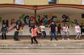 Auf einer Outdoor Bühne tanzen Jugendliche. Die Bühne ist mit Grafite besprüht.