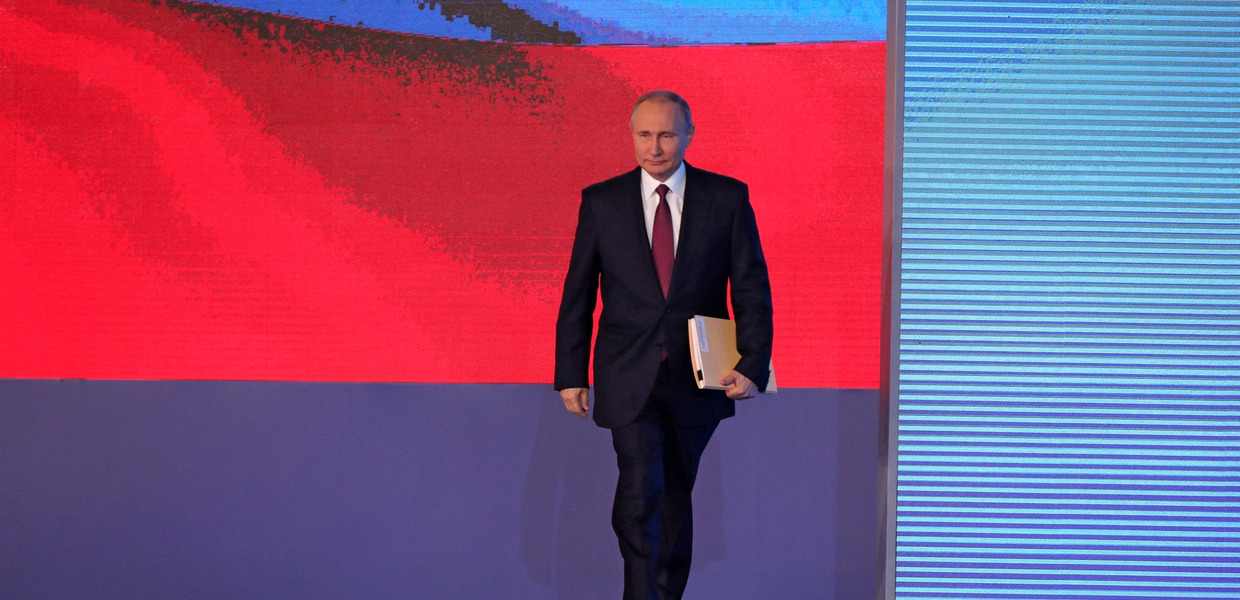 (© www.kremlin.ru / via Wikimedia Commons - CC-BY 4.0, http://creativecommons.org/licenses/by/4.0) Mit einer Dokumentenmappe unter dem Arm betritt Russlands Präsident Wladimir Putin eine Bühne, hinter der auf einem riesigen Bildschirm eine russische Flagge projiziert wird.