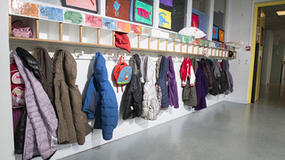 Ein Flur mit bunten aufgehängten Jacken in einer Schule.