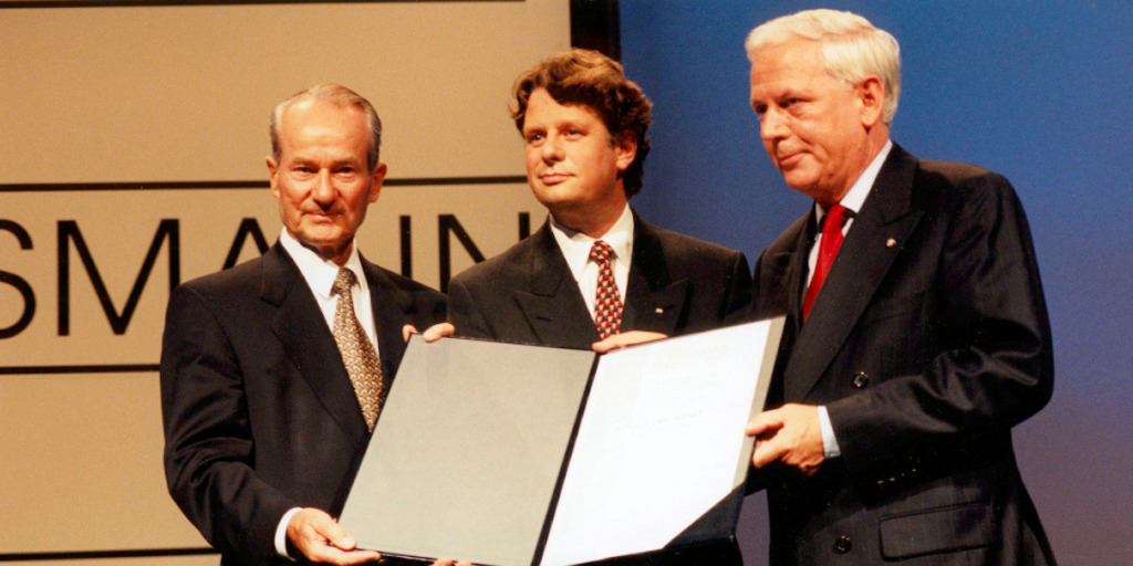 Reinhard Mohn übergibt den Carl Bertelsmann Preis 1997 an Lodewijk de Waal und Hans Blankert. Die drei Männer halten die Preis-Urkunde in die Kamera.