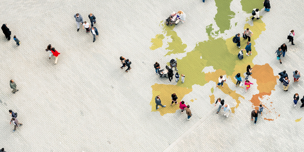 A lot of people walk a city center pavement mit a EU-logo on it.