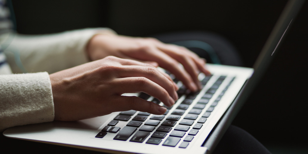 Eine Person tippt mit beiden Händen auf die Tastatur eines Laptops.