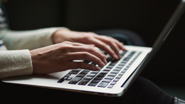 Eine Person tippt mit beiden Händen auf die Tastatur eines Laptops.