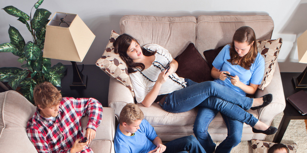 Zwei Jugendliche liegen gemütlich auf der Couch mit ihrem Handy