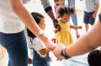 Kleine Kinder tanzen mit ihren Müttern im Kreis