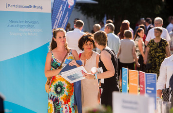 Eine Mitarbeiterin unterhält sich am Stand der Bertelsmann Stiftung und des Liz Mohn Centers auf dem Bürgerfest des Bundespräsidenten mit zwei Besucherinnen.