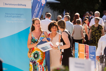 Eine Mitarbeiterin unterhält sich am Stand der Bertelsmann Stiftung und des Liz Mohn Centers auf dem Bürgerfest des Bundespräsidenten mit zwei Besucherinnen.