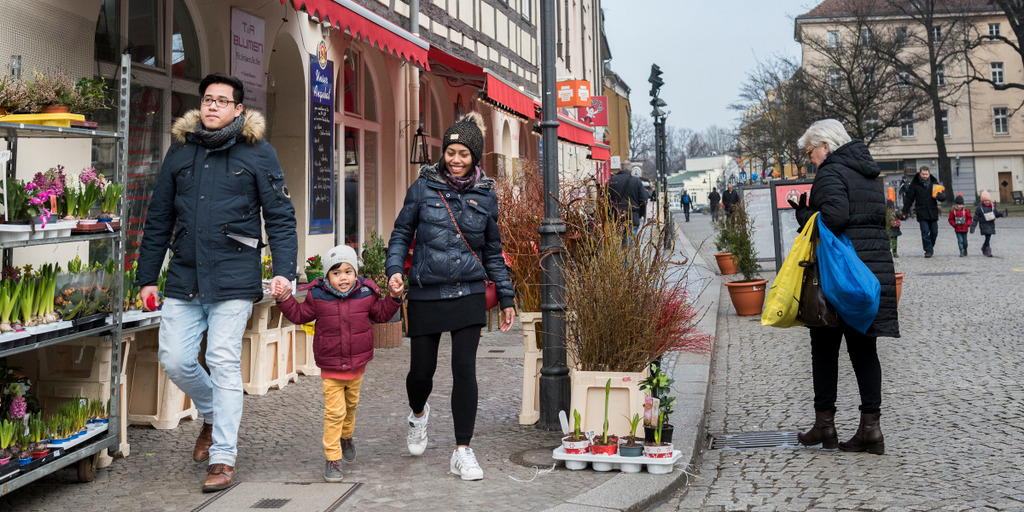 Ein Paar mit Migrationshintergrund läuft mit seiner Tochter durch die Altstadt von Berlin Spandau an einem Blumengeschäft vorbei.