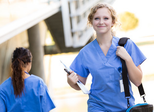 Eine Medizinstudentin geht mit einem Buch in der Hand an einer anderen Studentin vorbei