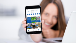 Eine Frau hält ein Handy hoch mit dem Profil des Kanals.