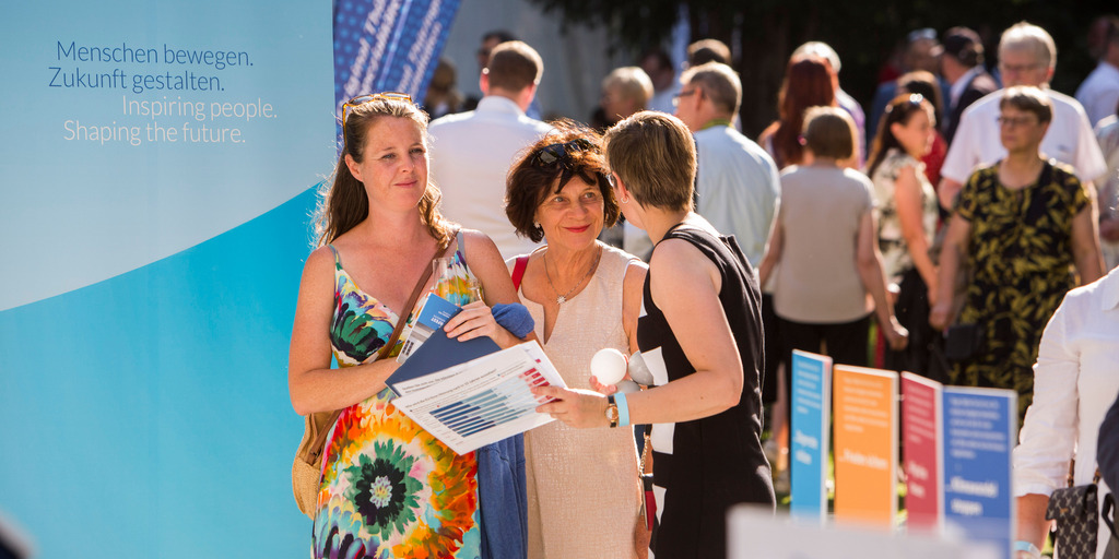 Daniela Schmidt, Projektmanagerin der Bertelsmann Stiftung, unterhält sich am Stand der Stiftung und des Liz Mohn Centers auf dem Bürgerfest des Bundespräsidenten mit zwei Besucherinnen.