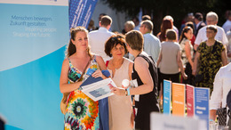 Daniela Schmidt, Projektmanagerin der Bertelsmann Stiftung, unterhält sich am Stand der Stiftung und des Liz Mohn Centers auf dem Bürgerfest des Bundespräsidenten mit zwei Besucherinnen.